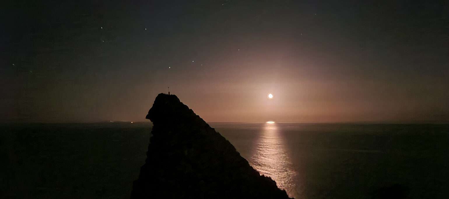 ceu noturno, com a lua refletida no mar e uma falésia da Macaronésia